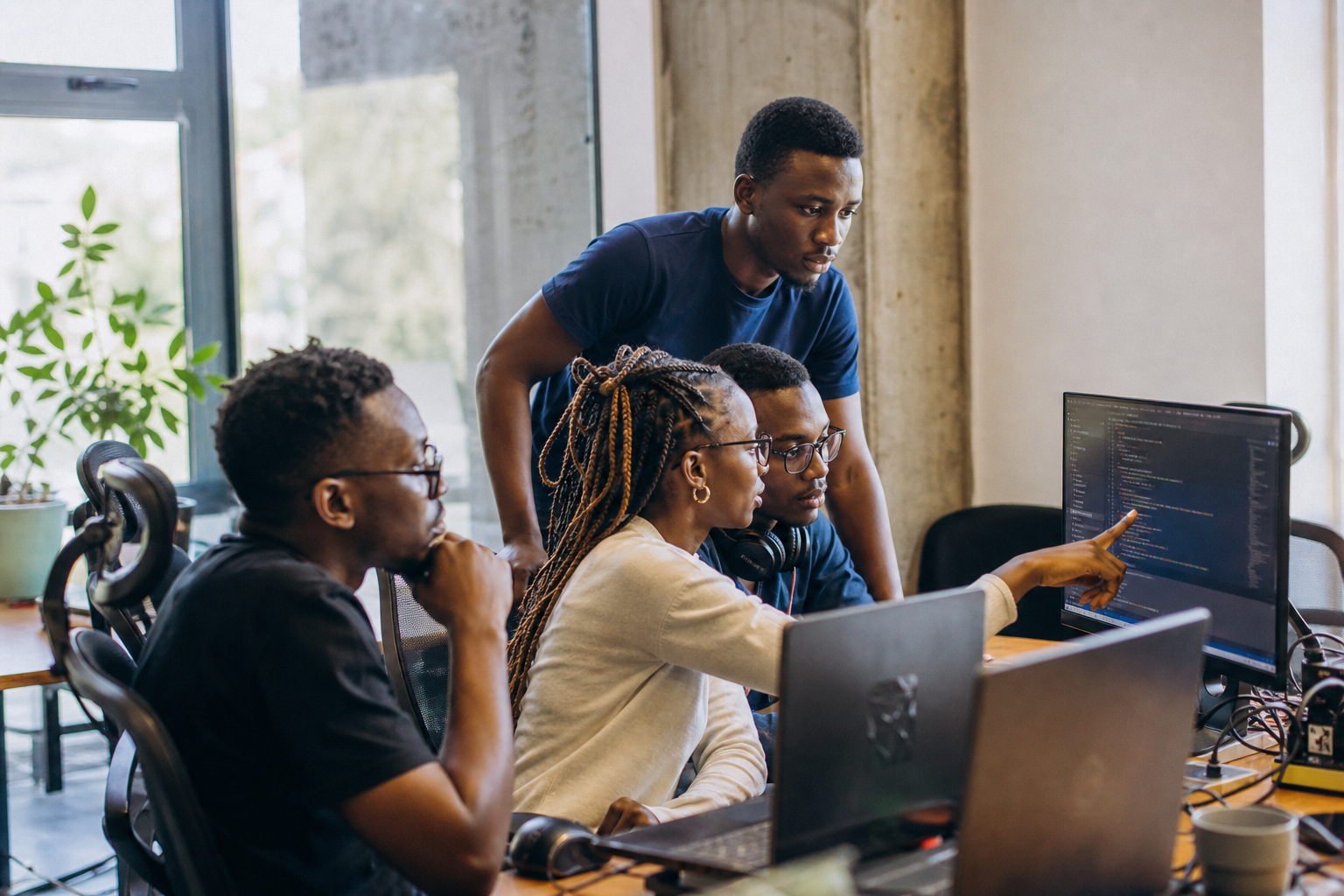 Devslab engineers collaborating around a monitor in the Kigali studio